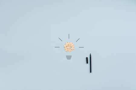 Light bulb made of blank puzzle pieces and hand drawn rays next to a black marker. Over blue background with copy space.の写真素材