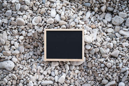 Top view of blank black chalk board placed on pebbles.の写真素材
