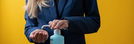 Closeup view of businesswoman applying hand disinfectant to her hands to prevent spreading of infectious virus.の写真素材