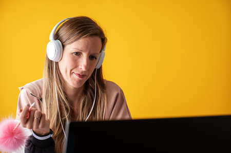 Young woman, student, studying from home listening to webinar with headphones on her.の写真素材