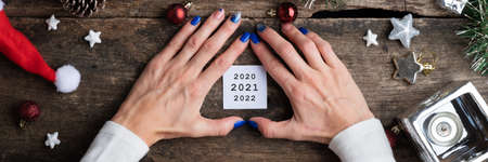 New year conceptual image - white post it paper with dates on it on a rustic wooden desk full of holiday ornaments.の写真素材