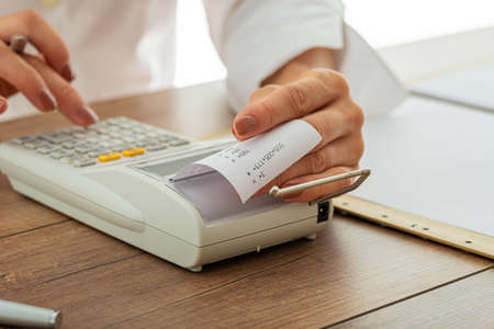 Closeup view of female hands using adding machine with printout receipt in a tax and accountancy image.の写真素材