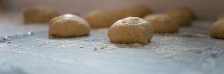 Wide view image of ball shaped pastry dough for bread or donut resting and rising on flour dusted...