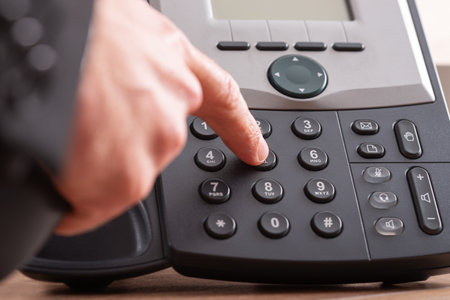 Closeup view of male finger dialing telephone number on black landline phone.の写真素材