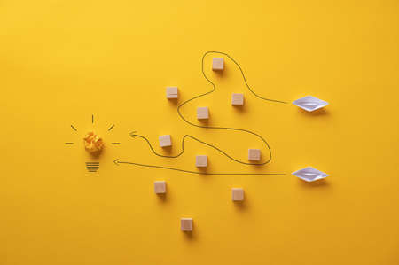 Two paper origami made boats trying to reach their goals and ambitions by travelling different paths.の写真素材