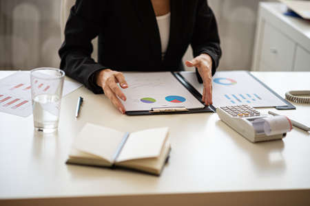 Businesswoman sitting at her desk working on financial report with graphs and charts.の写真素材