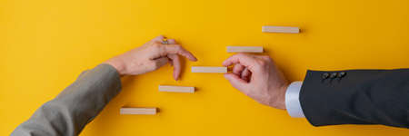 Hand of a businessman supporting a step in conceptual stairway for his female partner to walk her...
