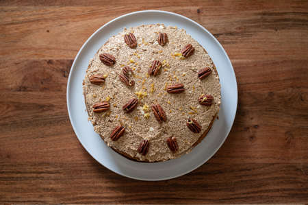 Top view of delicious vegan carrot cake decorated with walnuts on a wooden table.