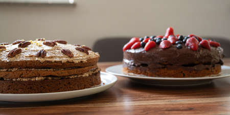 Low angle view of two delicious whole vegan cakes on a plate waiting on a dining table.の写真素材