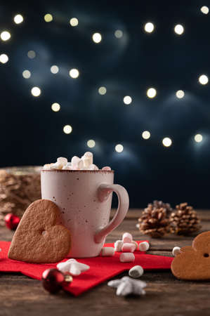 Cup of hot cocoa with tiny marsmallows placed in a festive christmas holiday setting with decoration...
