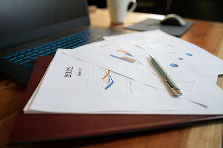 Low angle view of paperwork and documents with financial plan for the year 2022 lying on laptop...