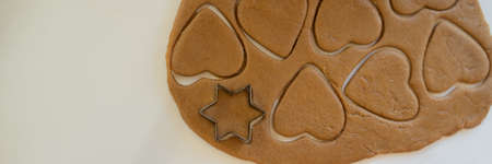 Top view of rolled vegan cookie dough with heart and star shaped cut cookies.