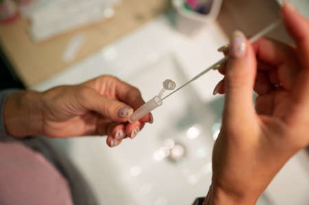 Closeup view of a woman dipping cotton swab stick in a solution from a covid19 self test kit.