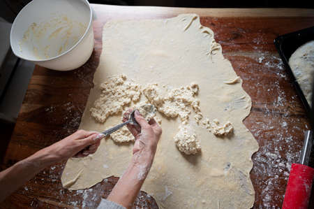 Overhead view of making homemade cottage cheese strudel with a rolled pastry dough on kitchen table.