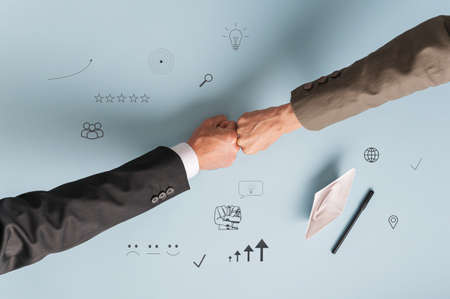 Top view of hands of businesspeople bumping fists over a vision board on blue background.の写真素材