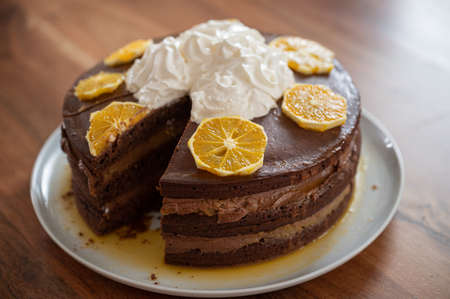 Delicious homemade vegan chocolate orange cake with a one missing piece on a plate.