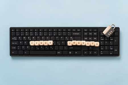 Conceptual image of online crime  - computer keyboard with wooden dice spelling cyber threats.