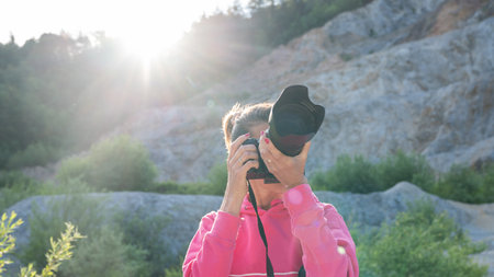 Female photographer taking photos of beautiful nature surrounded with quarry rocks at sunrise.