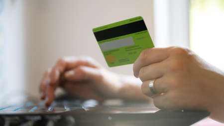 Closeup view of caucasian female hand holding credit card while browsing the internet on laptop...