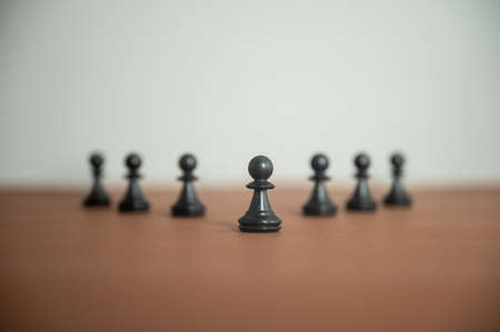 Low angle view of chess pawn figures placed in a pyramid shaped line on brown surface in a conceptual image of power and teamwork.の写真素材