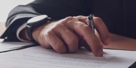 Wide view image of a businessman hand with elegant watch on his wrist holding and ink pen. Closeup view.の写真素材