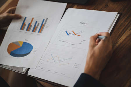 Over the shoulder view of a businesswoman reviewing business and economic report with graphs and charts representing annual finances.の写真素材