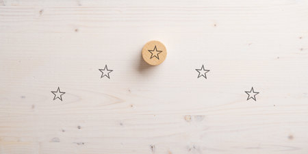 Five stars positioned in a pyramid shape with the top one drawn on wooden cut circle. Over white wooden background.の写真素材