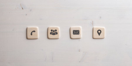Contact and communication icons on four wooden cut squares placed over wooden background.の写真素材