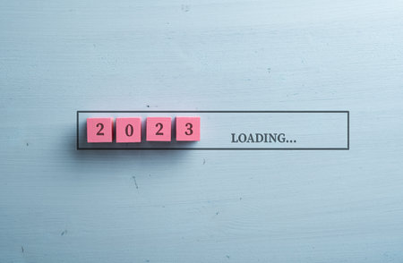 2023 Loading sign spelled over pink wooden blocks and blue wooden background in a conceptual image of a proximity of new year.の写真素材