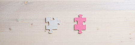 Wide view image of two matching puzzle pieces placed over wooden background with copy space