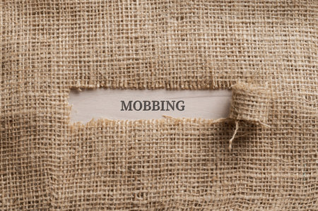 Top view of a rough linen fabric with a torn window in the middle with the word MOBBING written in it.の写真素材