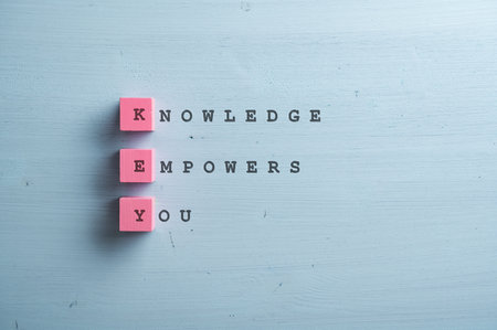 Knowledge empowers you sign written on pink wooden blocks and blue wooden backgorund.の写真素材