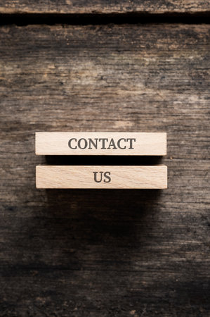 Contact us sign written on two wooden pegs placed over rustic wooden background.の写真素材