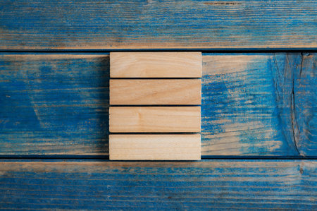 Stack of four blank wooden blocks or pegs placed over aged blue background.の写真素材