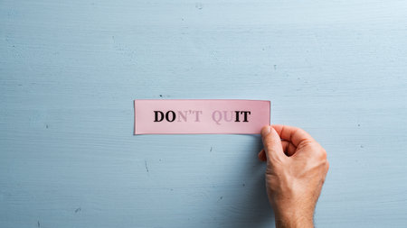 Male hand placing a pink paper with  Dont quit sign vanishing into a do it sign on a blue wooden background.の写真素材