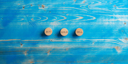 Three wooden cut circles with word Buy, Sell and Gold written on them placed over blue wooden background.の写真素材