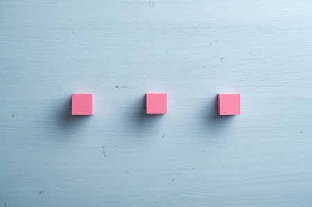 Three blank pink wooden blocks placed over pastel blue wooden background.の写真素材