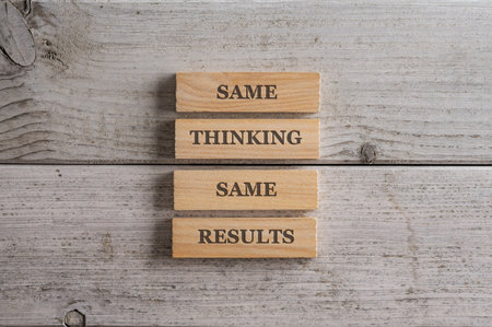 Same Thinking Same results sign written on four stacked wooden pegs placed over white wooden background.の写真素材