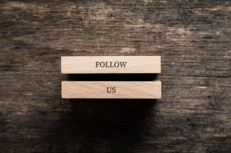 Follow us sign written on two wooden pegs placed over rustic wooden background.の写真素材