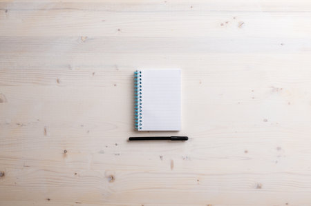 Top view of blank spiral notebook with black marker under it placed on plain simple wooden background. With copy space.の写真素材