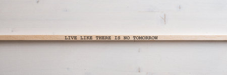 Wide view image of a wooden slat with a Live like there is no tomorrow sign on it placed over plain simple wooden background.の写真素材