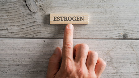 Male hand placing a wooden peg with an Estrogen sign on it over a white wooden background.の写真素材