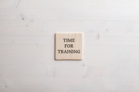 Wooden tile with a Time for training sign on it placed over plain simple wooden background.の写真素材