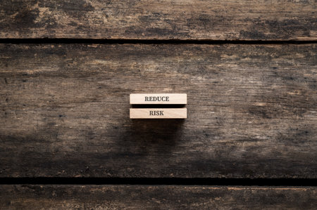 Reduce risk sign written on two stacked wooden pegs placed over textured rustic wooden background.の写真素材