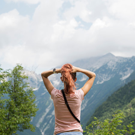 View from behind of a young woman enjoying in beautiful nature with mountain view.の写真素材