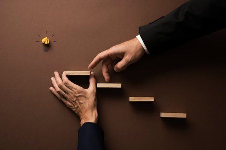 Hand of a businessman walking his fingers up the stairs supported by his female colleague to realise an idea.の写真素材