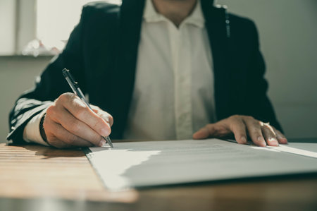 Front view of a torso of a businessman or a lawyer signing a contract or document sitting at his office desk.の写真素材