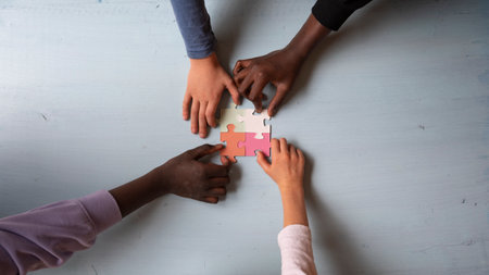 Top view of four children of mixed races  matching colorful puzzle pieces in a conceptual image of unity and friendship.の写真素材