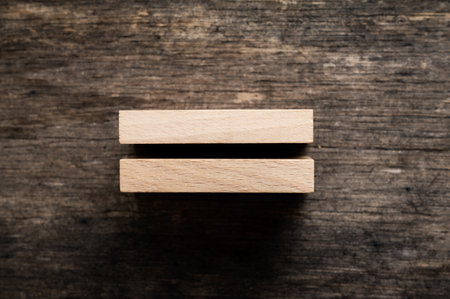 Two stacked blank wooden pegs placed over textured rustic wooden background.の写真素材