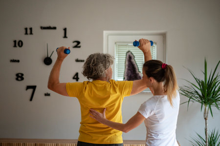 Professional trainer or physiotherapist working with a senior man, showing him the correct posture during strength exercise. Healthy and active retirement lifestyle.の写真素材